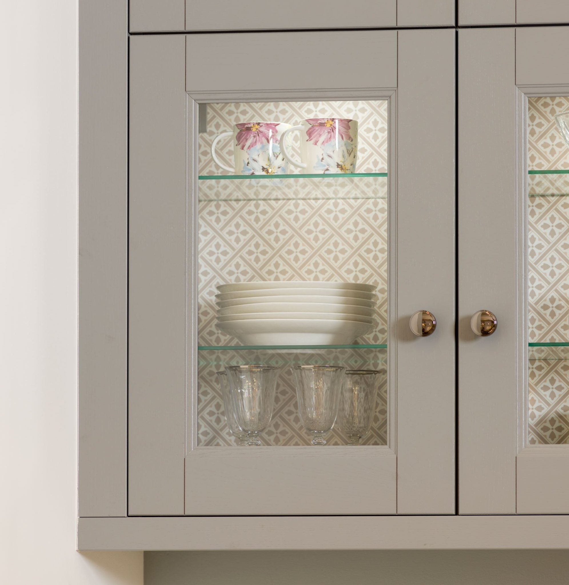 Crofts & Assinder handles on a cabinet displaying mugs, plates and wine glasses.